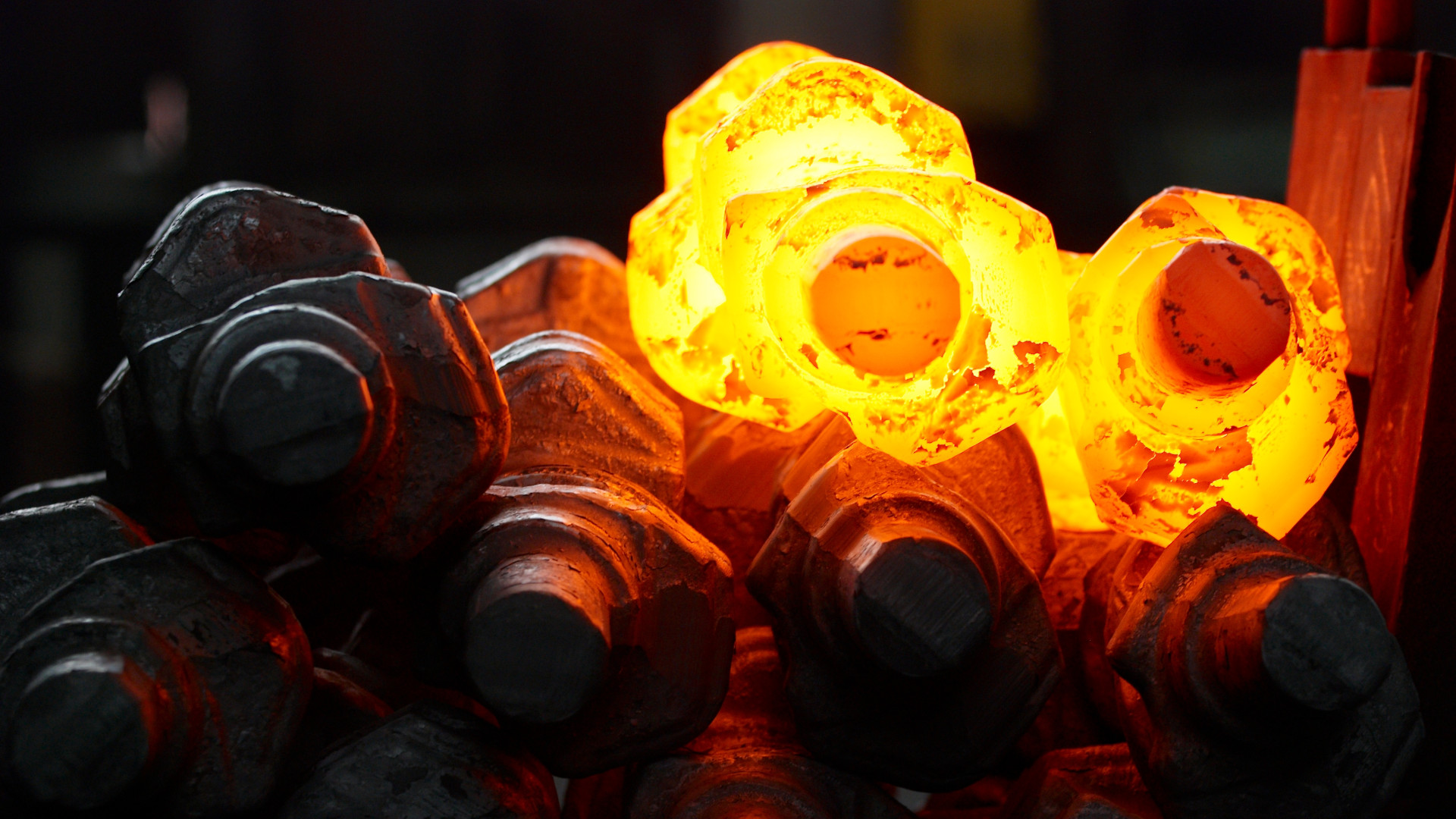 Glowing hot crankshaft undergoing heat treatment in industrial forging process for automotive manufacturing.